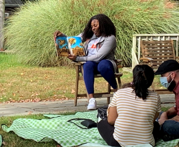 Volunteer reading to families in a park