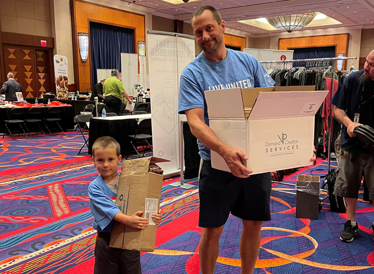 A father and son carrying boxes to help volunteer collecting donated items