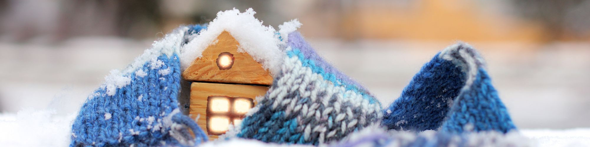 A small toy home with snow and a winter scarf around it
