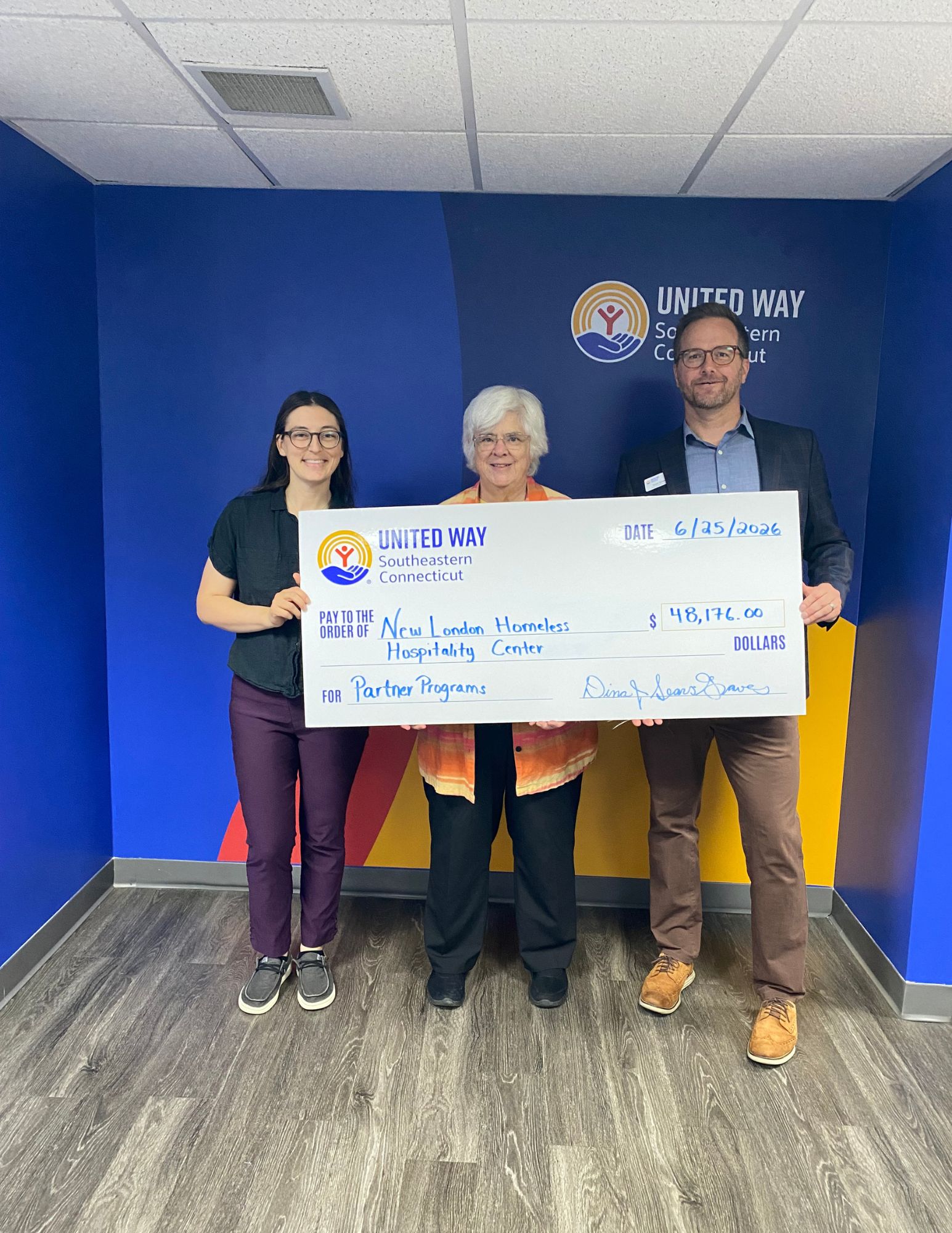 Carli Herz (left) and Scott Umbel (right) of UWSECT award partner program funding to the New London Homeless Hospitality Center.