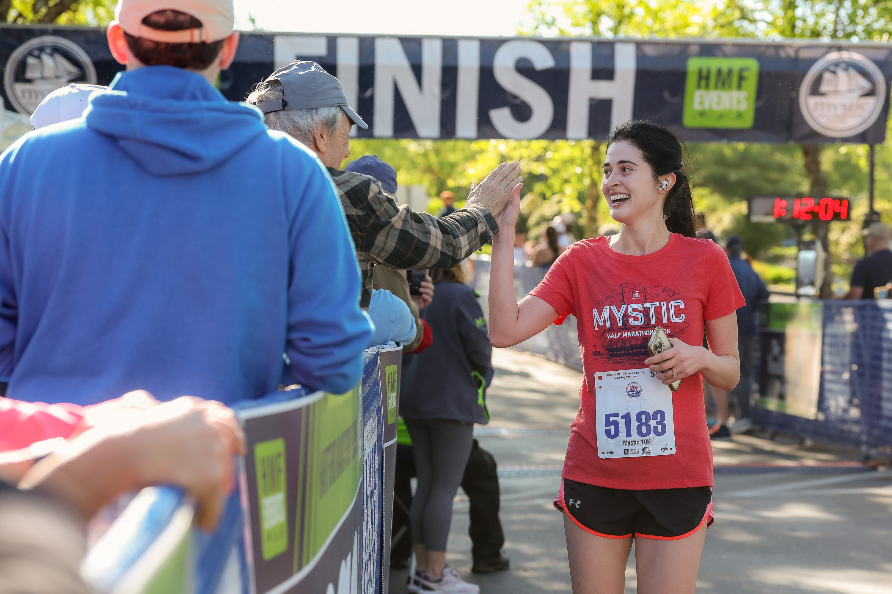 Photo of a female running high-fiving a spectator after completing the Mystic Half Marathon