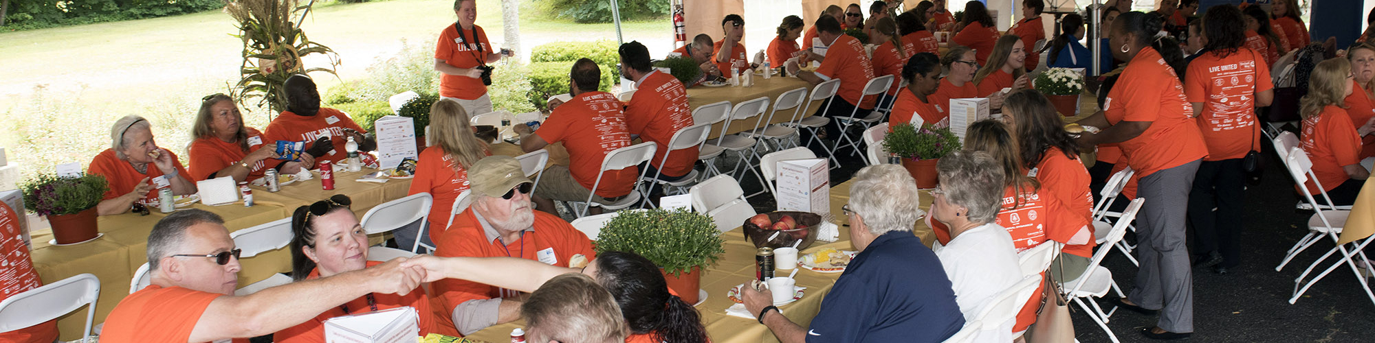 United Way supporters sitting at long tables at a cookout event