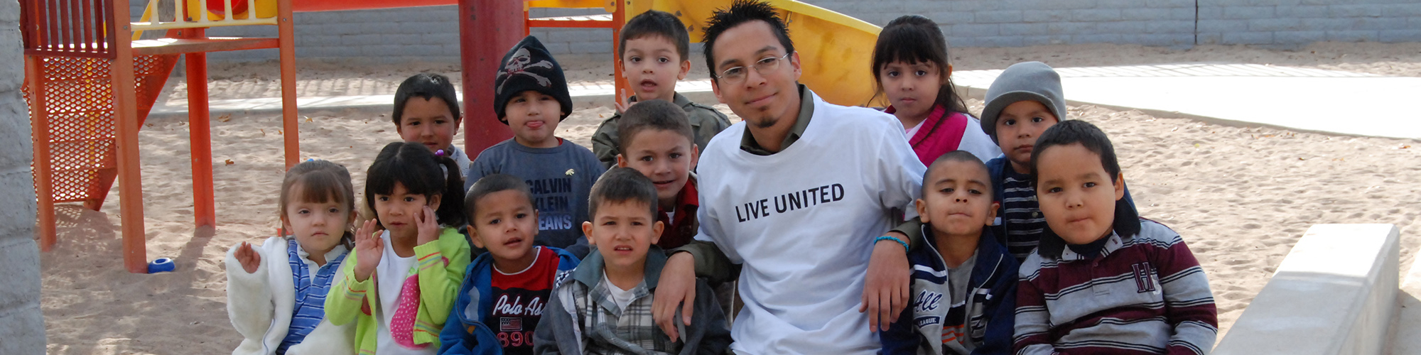 United Way volunteer surrounded by young children on a playground