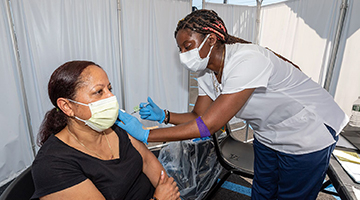 A woman receiving a vaccine shot by a nurse at a mobile health clinic